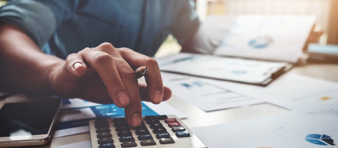 Business accounting concept, Business man using calculator with computer laptop, budget and loan paper in office.